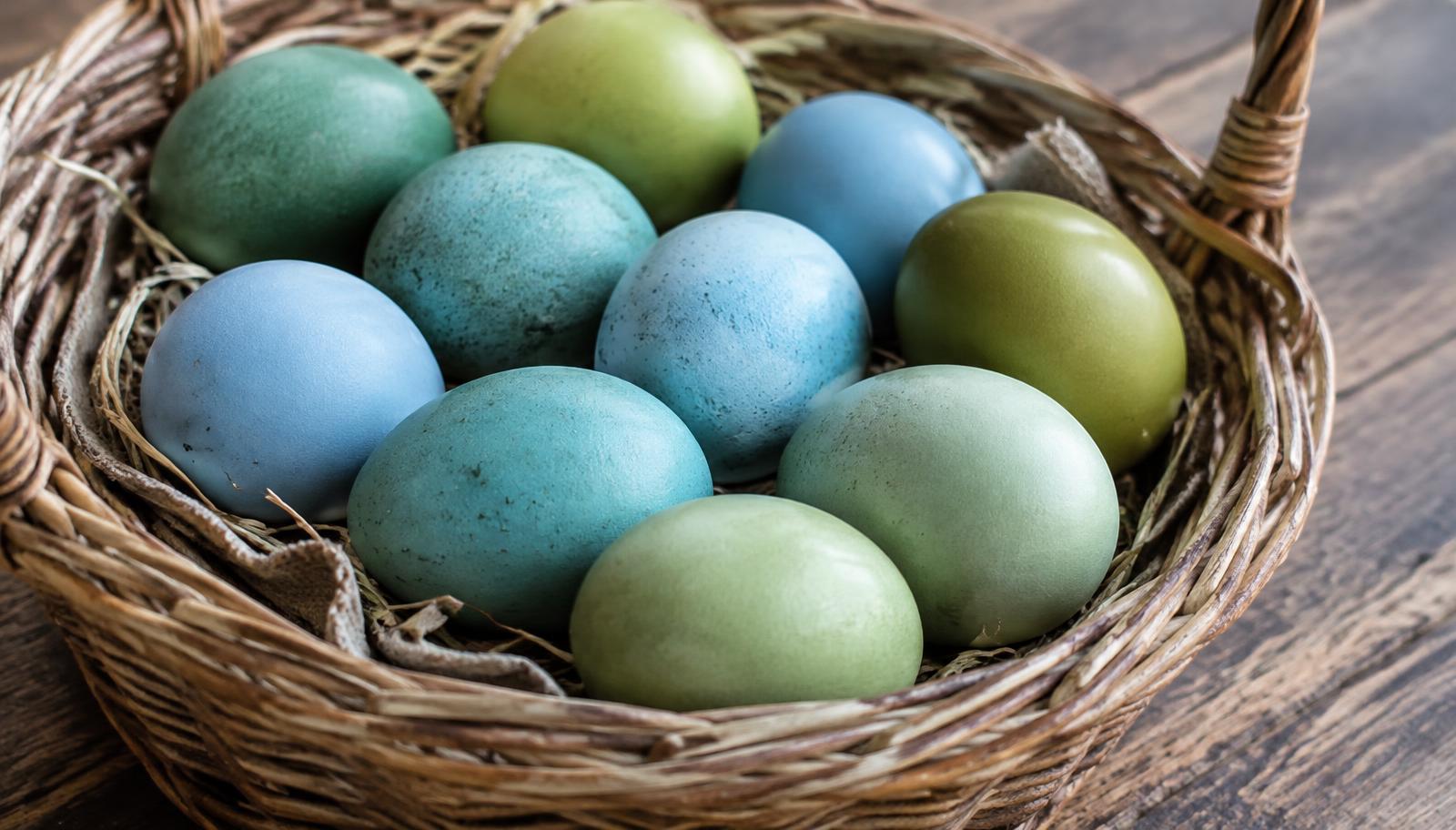 Panier d'œufs bleus, bleu-vert et vert olive sur une table en bois